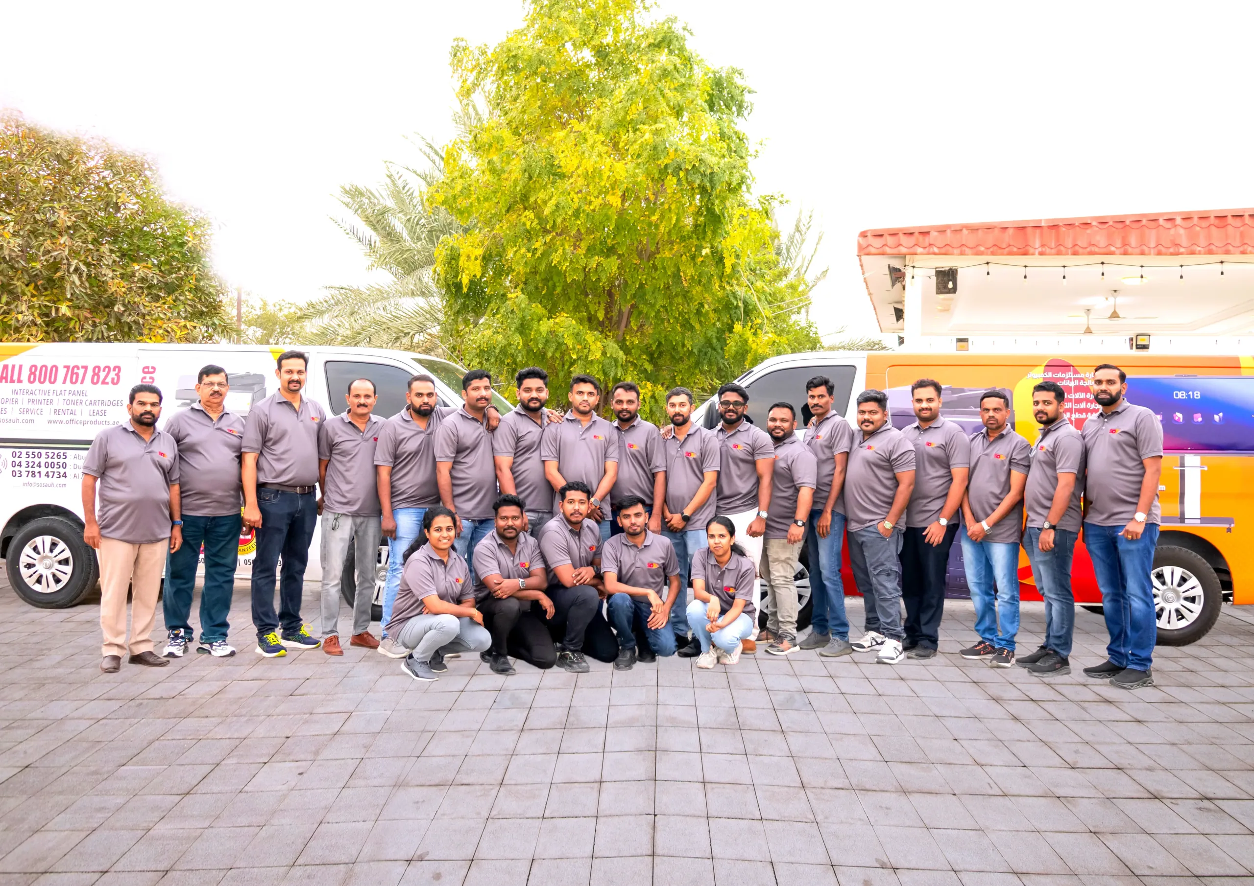 SOS IT Trading team in matching uniforms standing beside company vehicles.